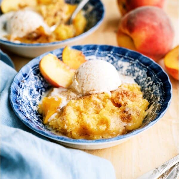 A serving of Peach Cobbler Dump Cake (4 Ingredients) in a bowl with ice cream.
