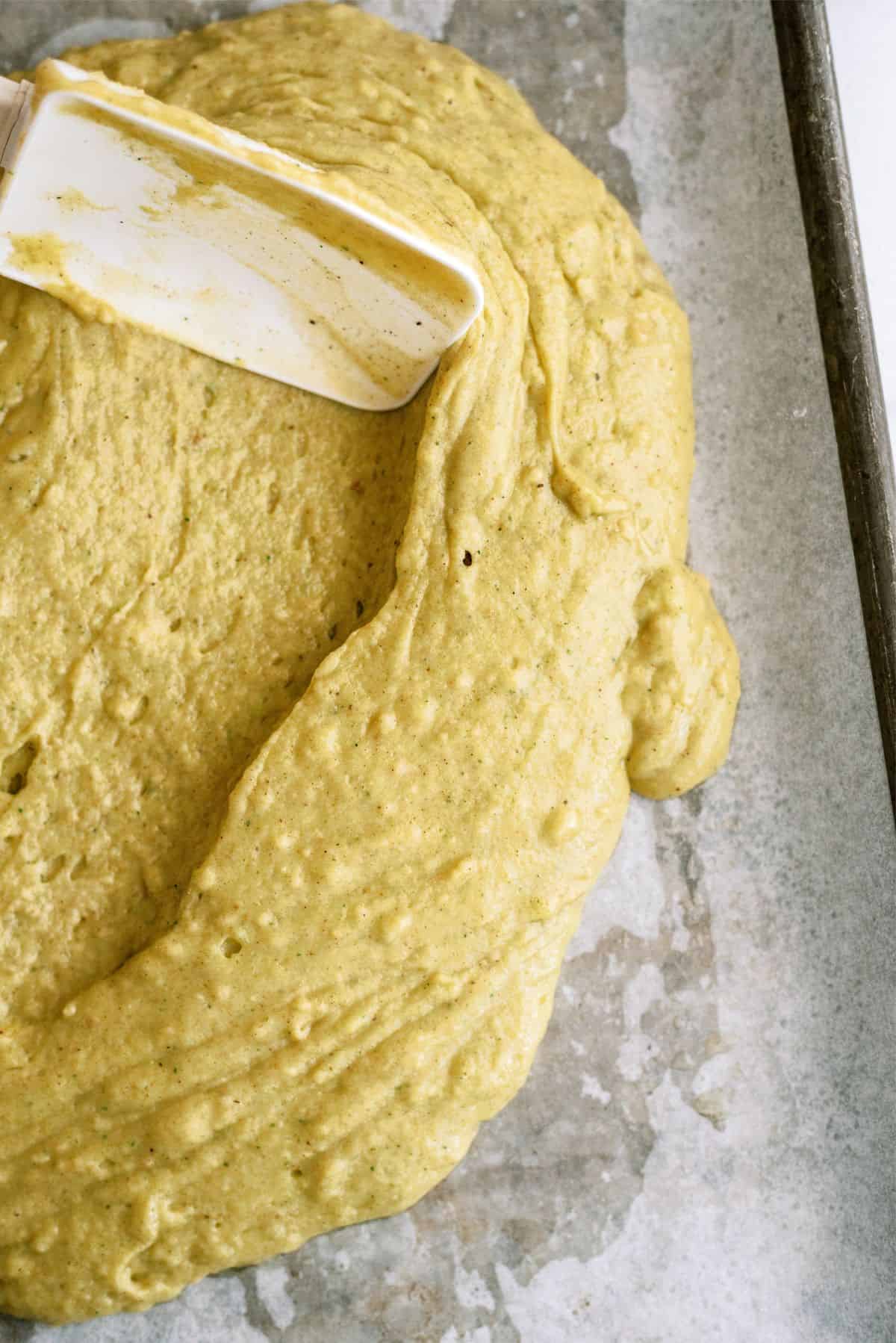 Spreading Sheet Pan Zucchini Cake batter into pan with a spatula.