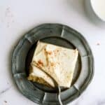 A fork slicing a bite of a slice of Sheet Pan Zucchini Cake with Frosting on a plate.
