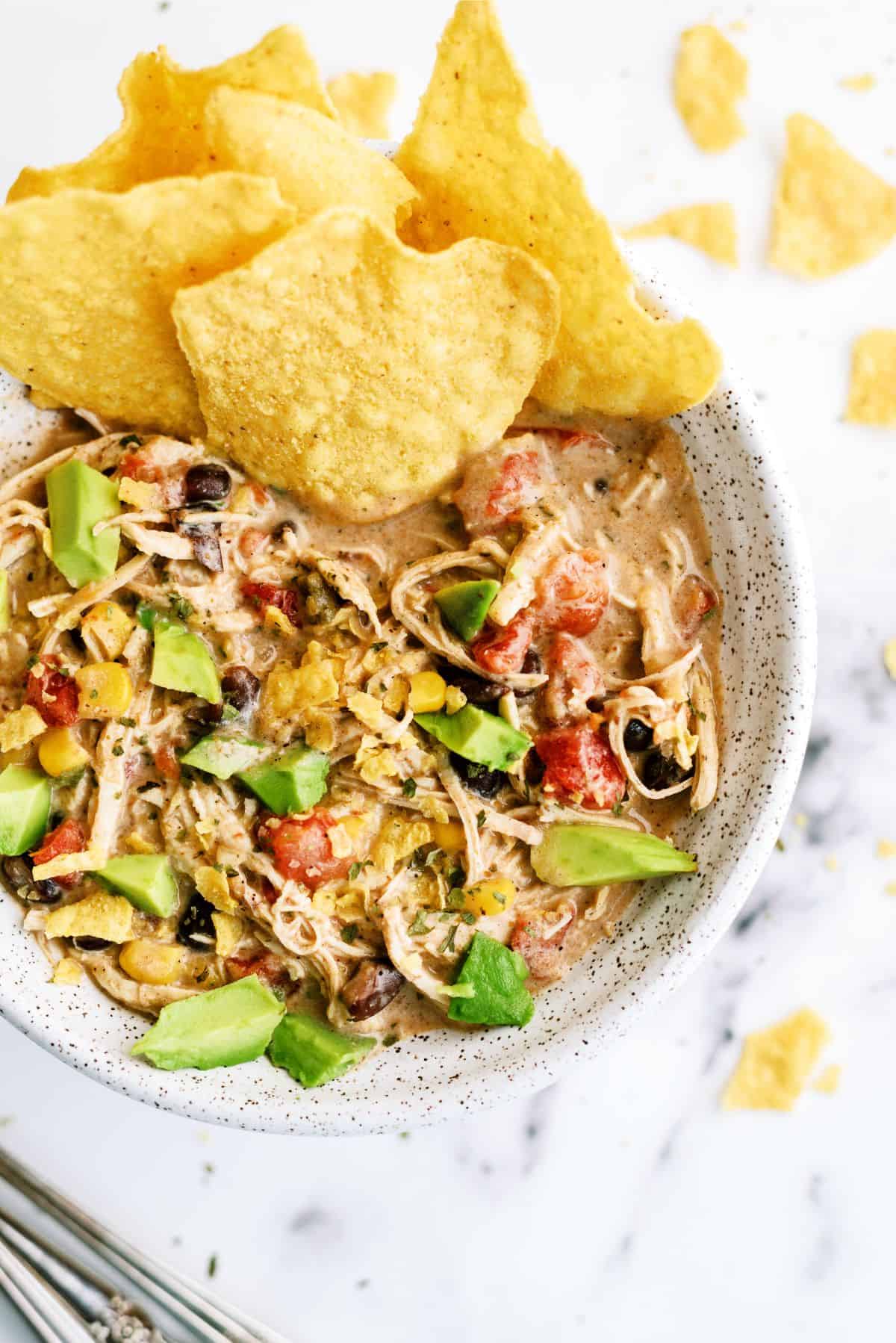 A serving of Slow Cooker Cream Cheese Chili in a bowl with a side of tortilla chips