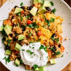 Top view of a serving of Zucchini Taco Casserole on a plate with sour cream.