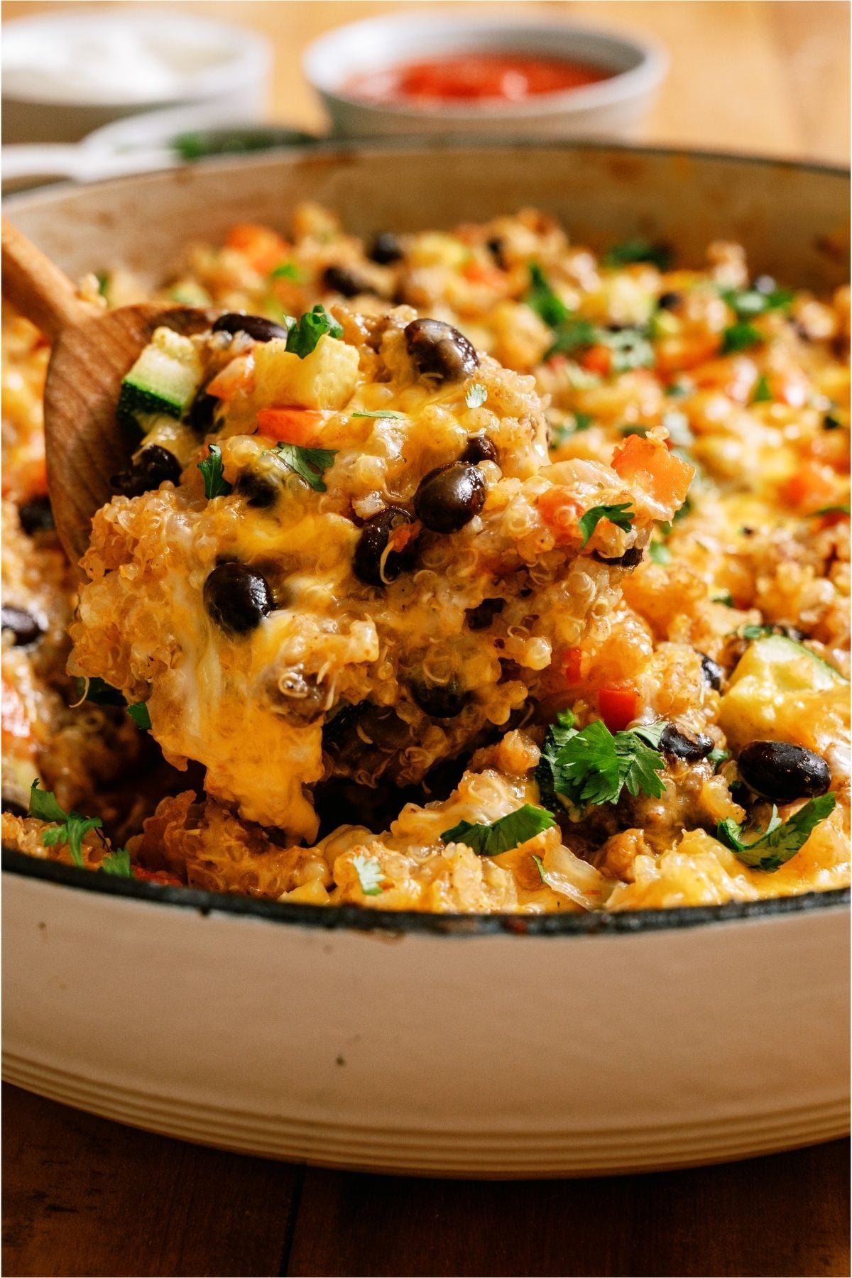Zucchini Taco Casserole in a skillet with a wooden spoon lifting out a scoop.