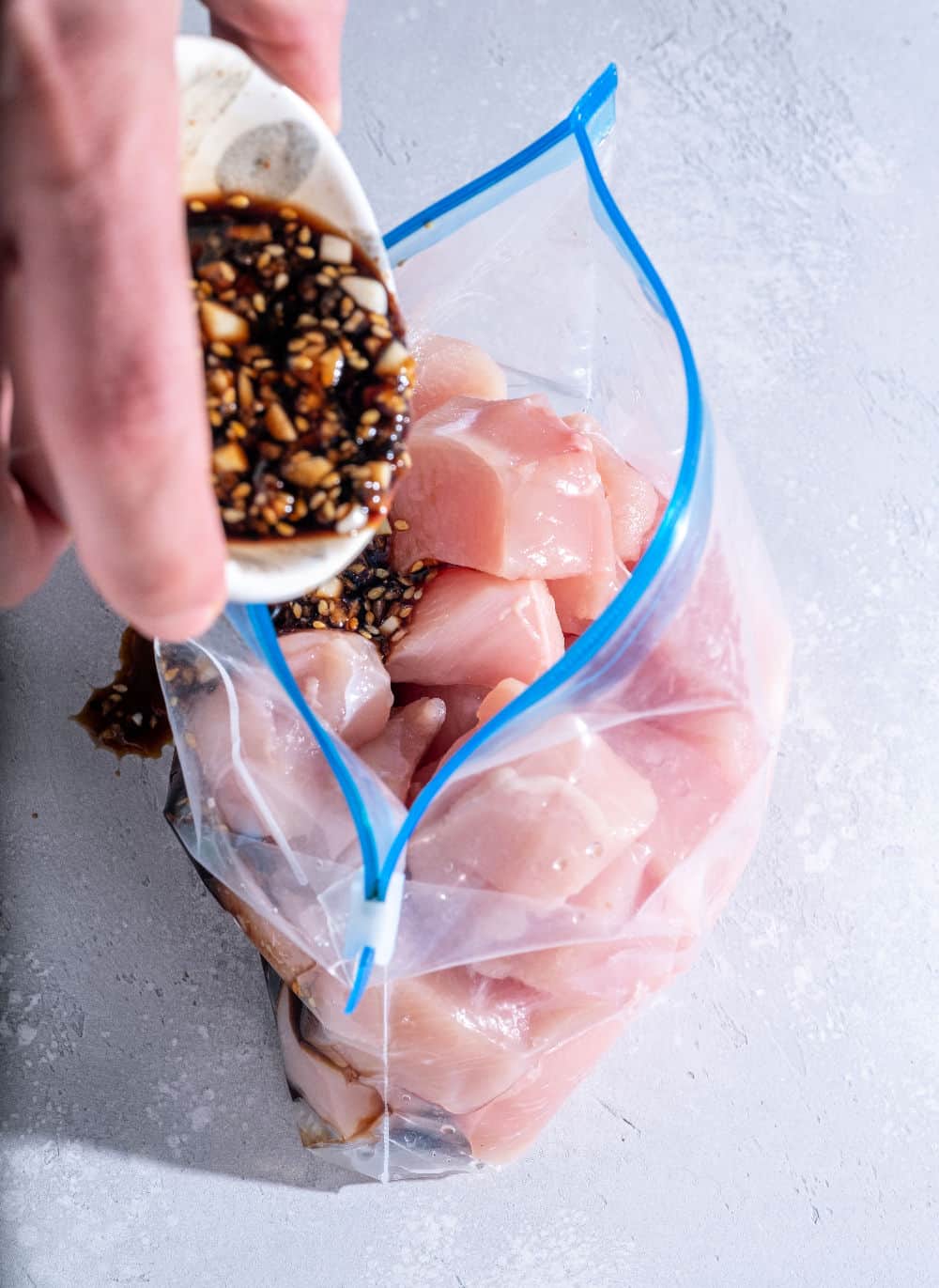 prepping a freezer meal with sauce and raw chicken