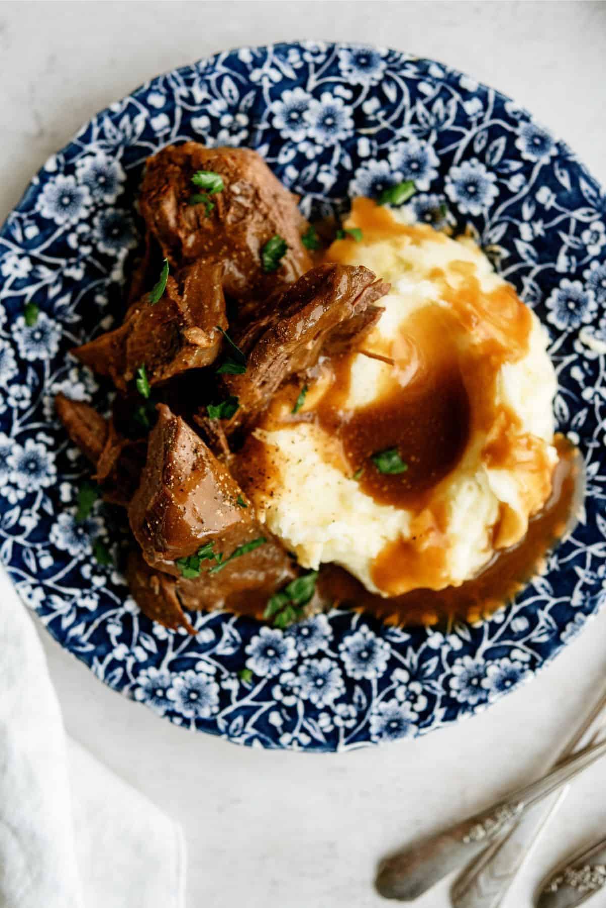 Delicious Texas Roadhouse-style pot roast served with mashed potatoes and gravy.