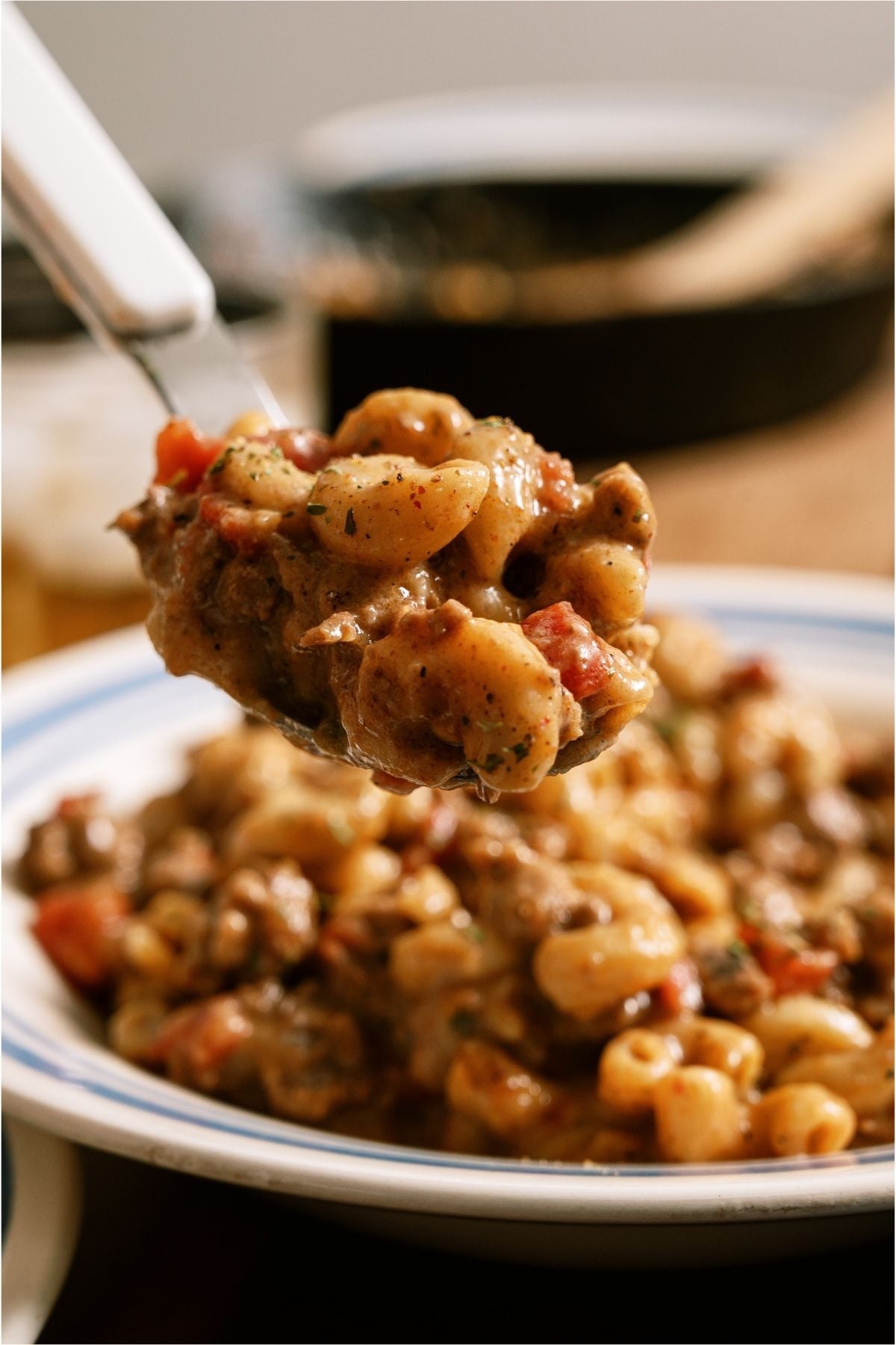 A spoon lifting a bite of Cheeseburger Macaroni out of the bowl.