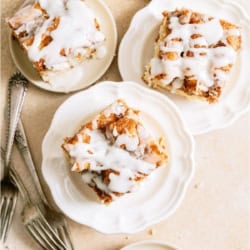 Several plates with slices of Cinnabon Cinnamon Roll Cake on them.