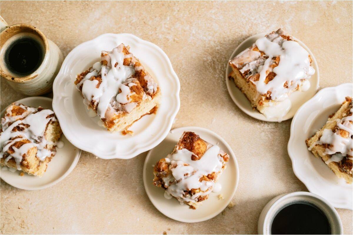 Top view of several plates with slices of Cinnabon Cinnamon Roll Cake on them.