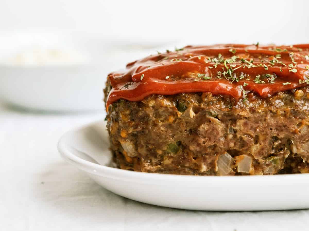 Side view of a loaf of Copycat Cracker Barrel Meatloaf on a serving plate.