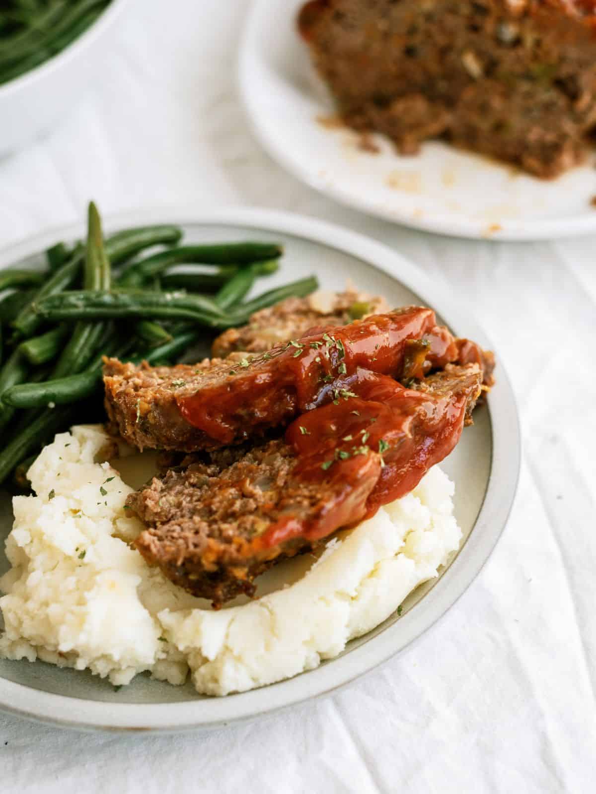 Slices of Cracker Barrel Meatloaf Copycat on a plate with potatoes and beans