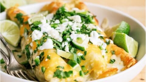 Two Honey Lime Chicken Enchiladas on a plate, topped with cheese and cilantro.