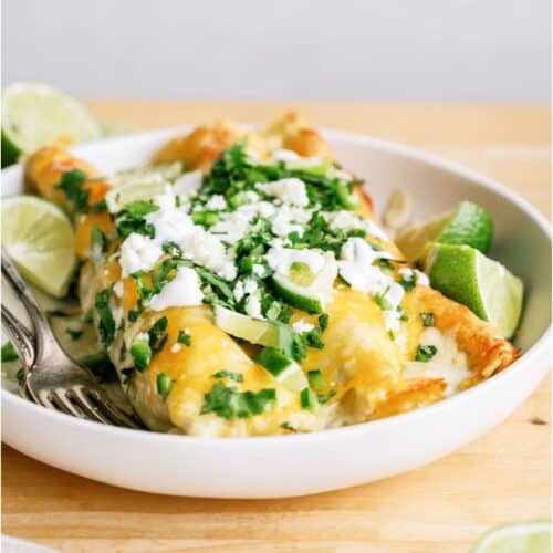 Two Honey Lime Chicken Enchiladas on a plate, topped with cheese and cilantro.