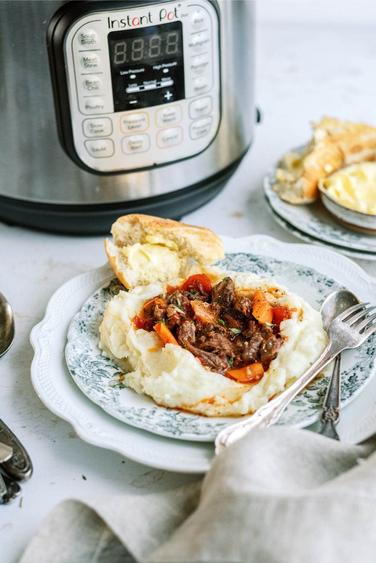 Instant Pot Beef Daube Stew with Mashed Potatoes on a plate with the Instant Pot in the background