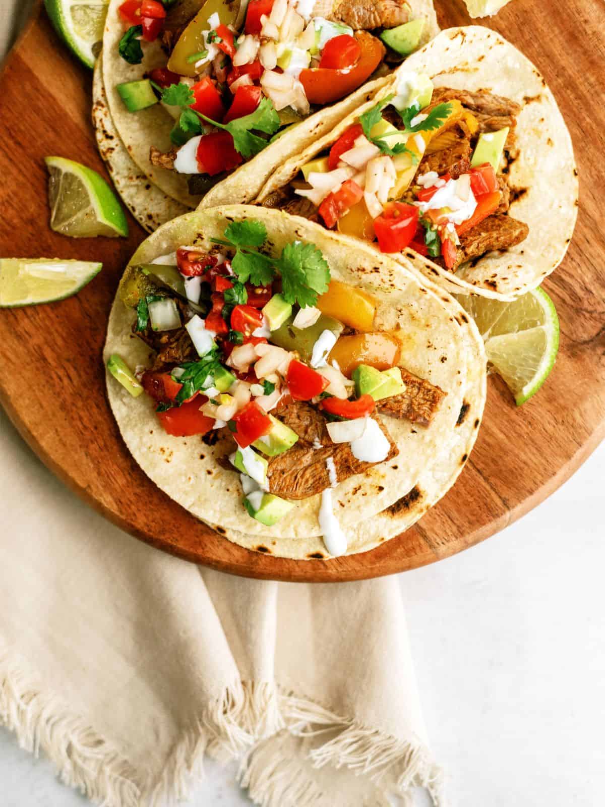 Instant Pot Steak Fajitas in tortillas on a cutting board