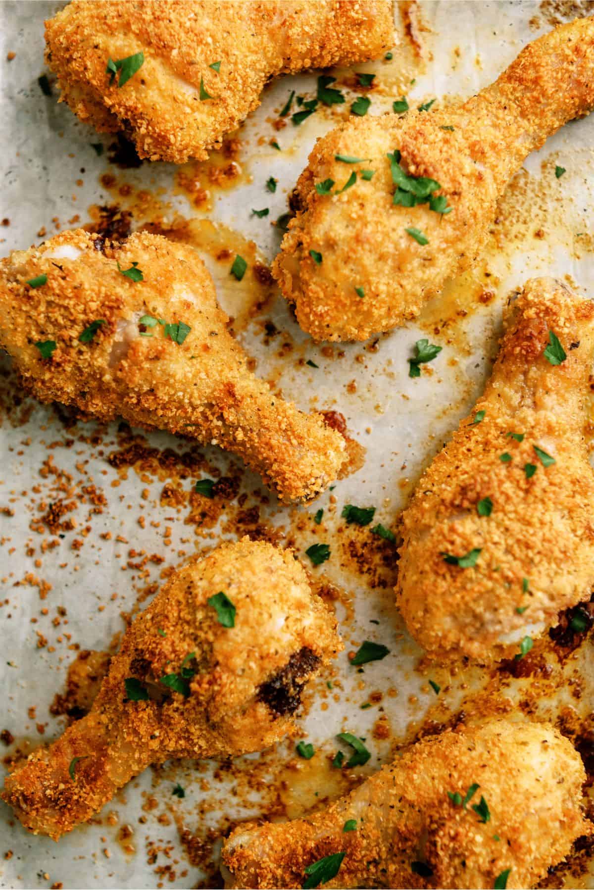 Oven-Fried Parmesan Chicken Drumsticks on a baking sheet