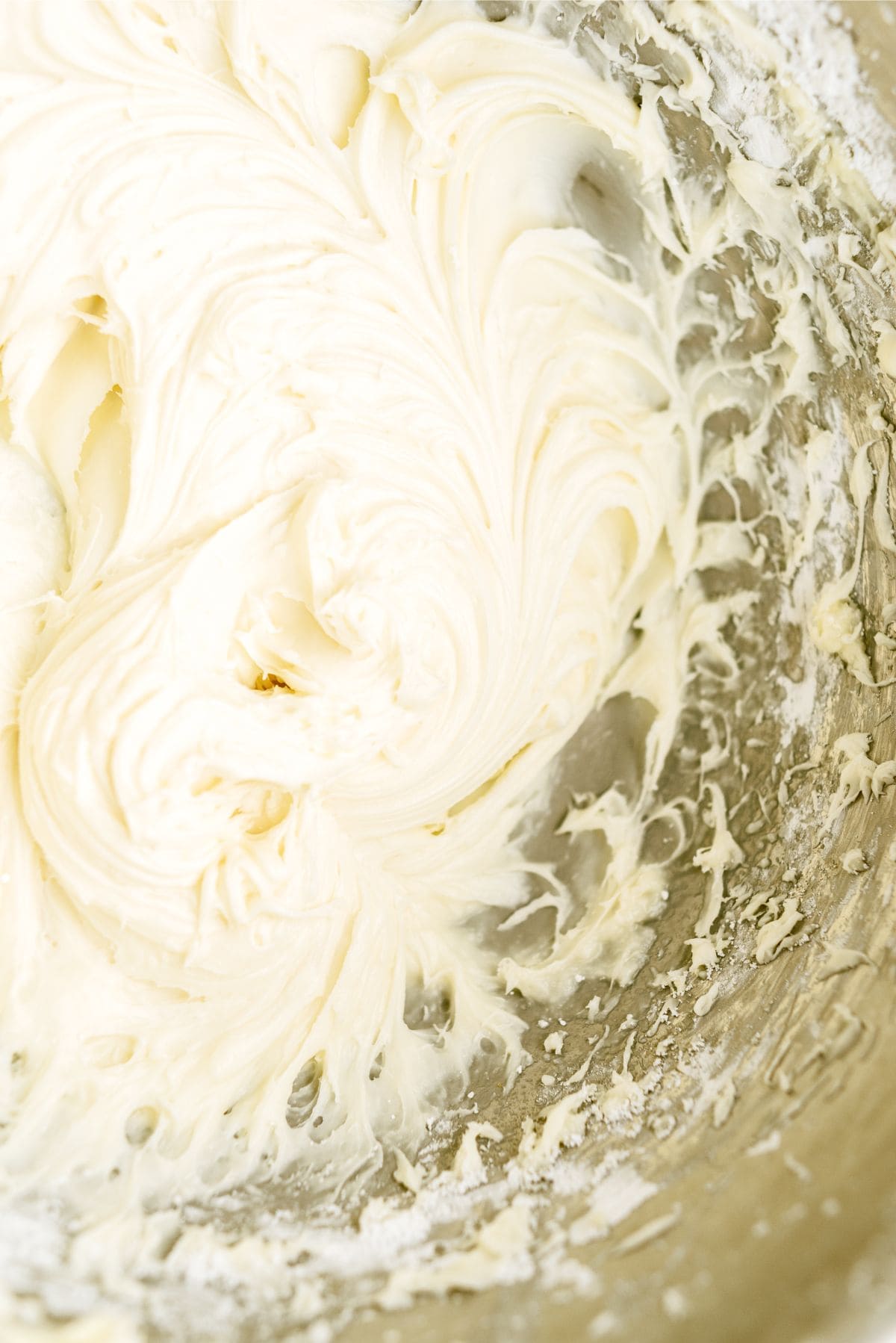 Close-up of creamy, whipped mixture with a smooth and swirled texture inside a mixing bowl.