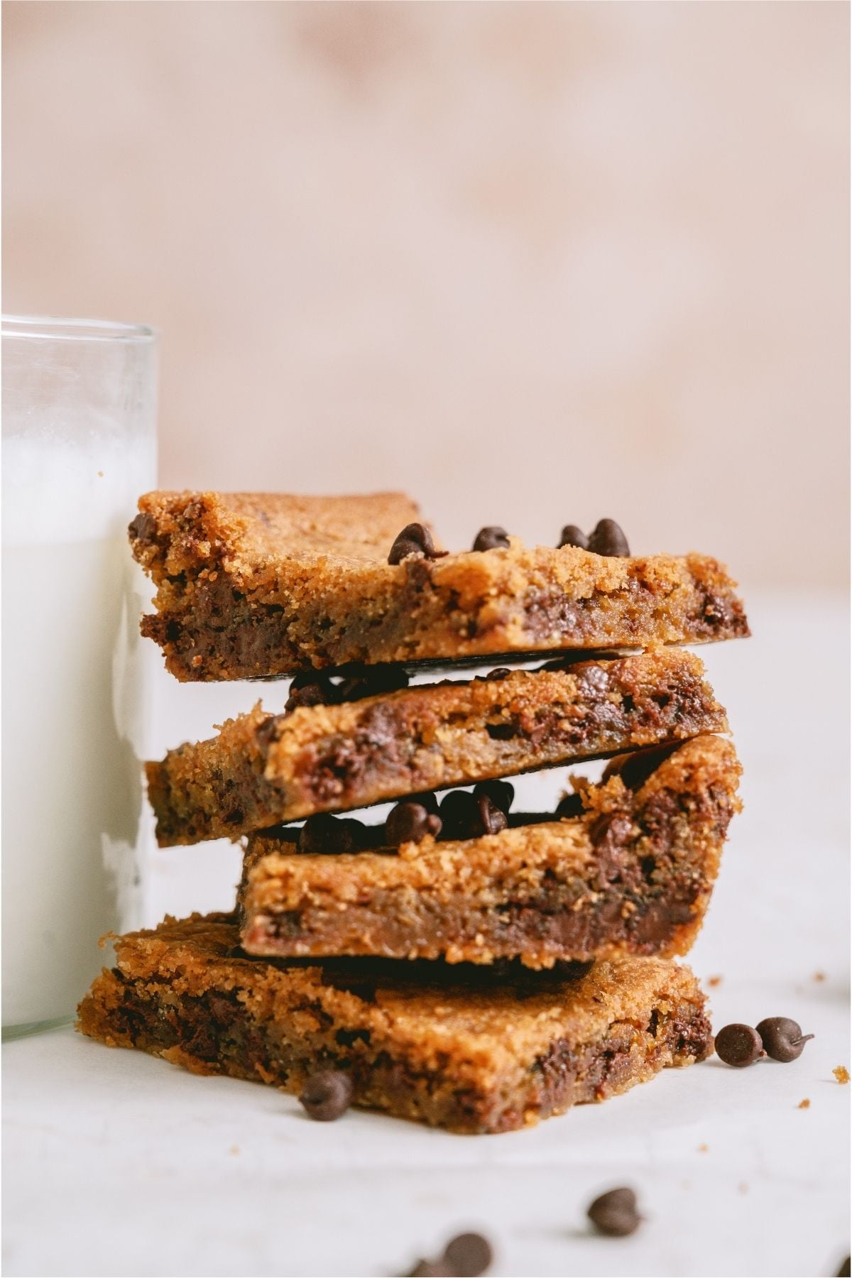 Sheet Pan Chocolate Chip Cookie Bars stacked next to a glass of milk.