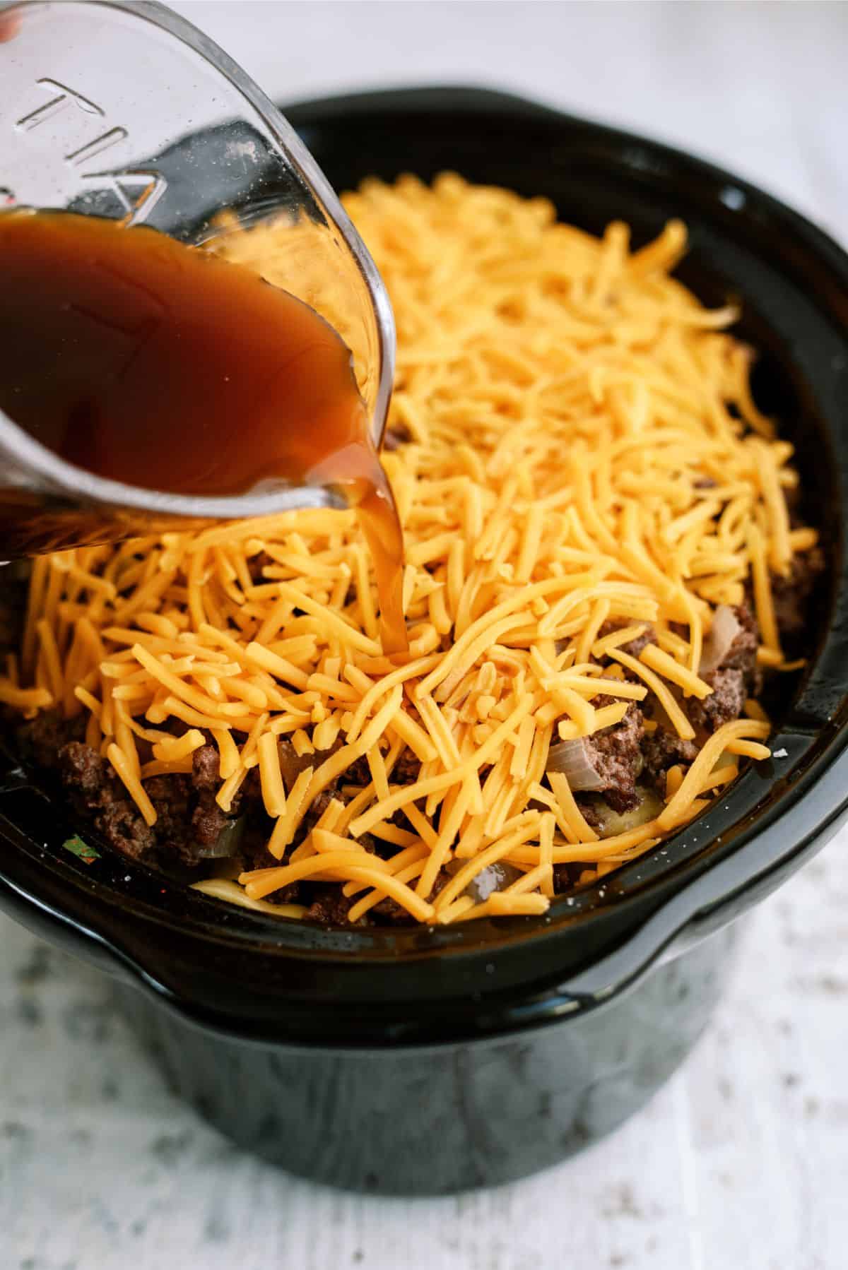 Pouring broth on top of ingredients in slow cooker