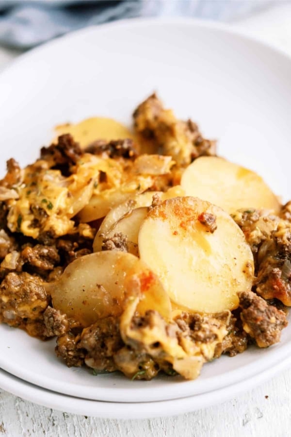 Close-up of a casserole dish containing layers of sliced potatoes, ground meat, and a cheese topping.