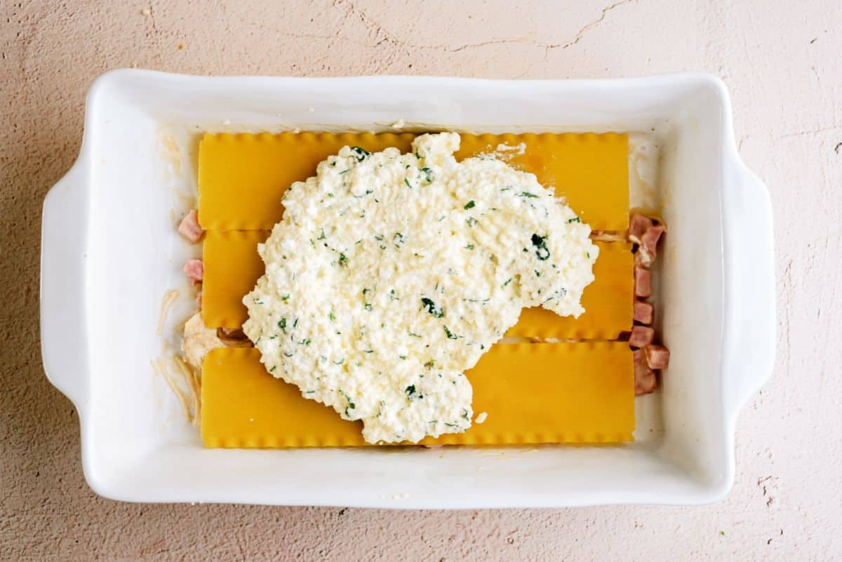 Cheese mixture on top of lasagna noodles in casserole dish