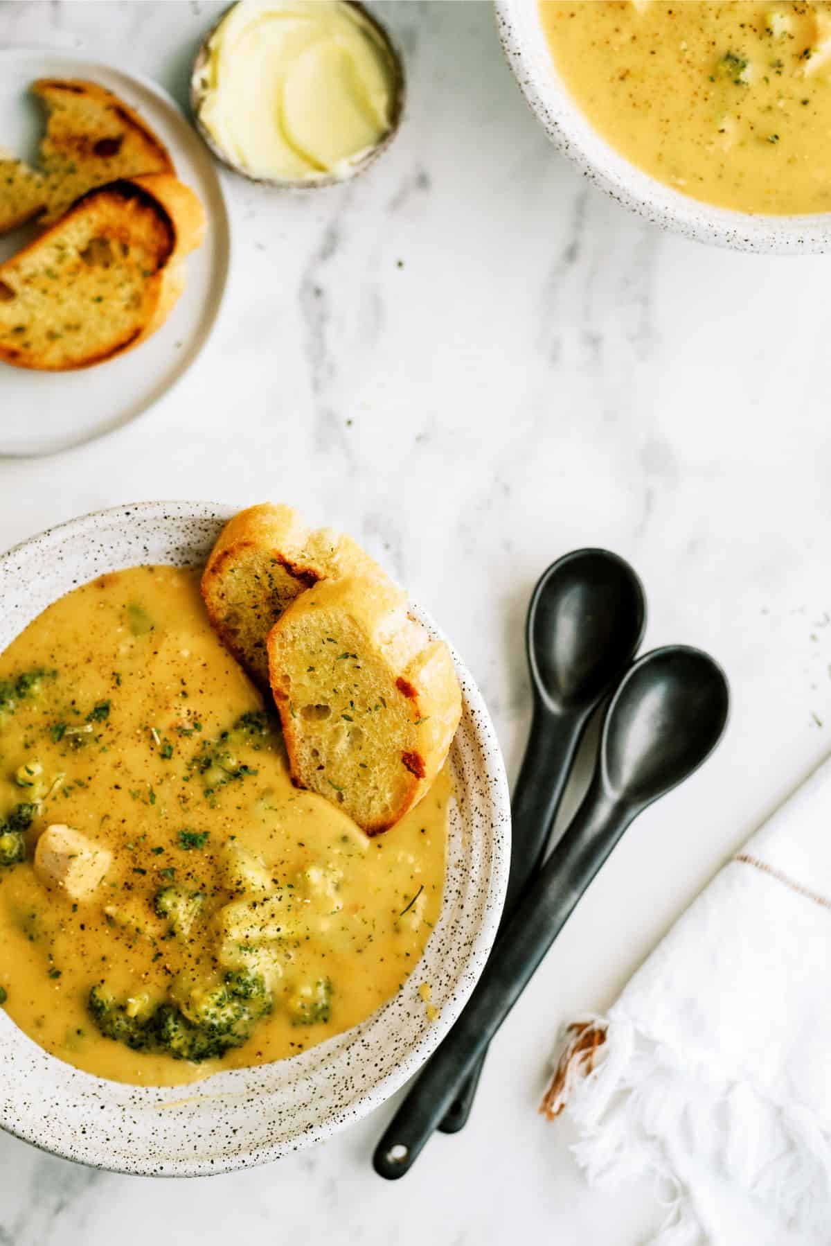 A bowl of Chicken and Broccoli Cheese Soup with a side of bread