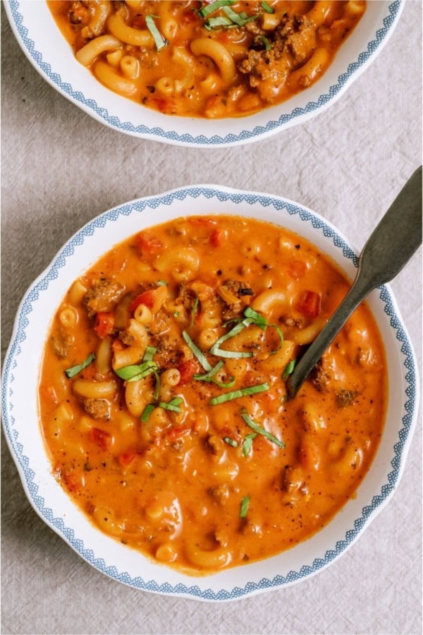 Top view of 2 bowls of Creamy Ground Beef and Tomato Macaroni Soup,