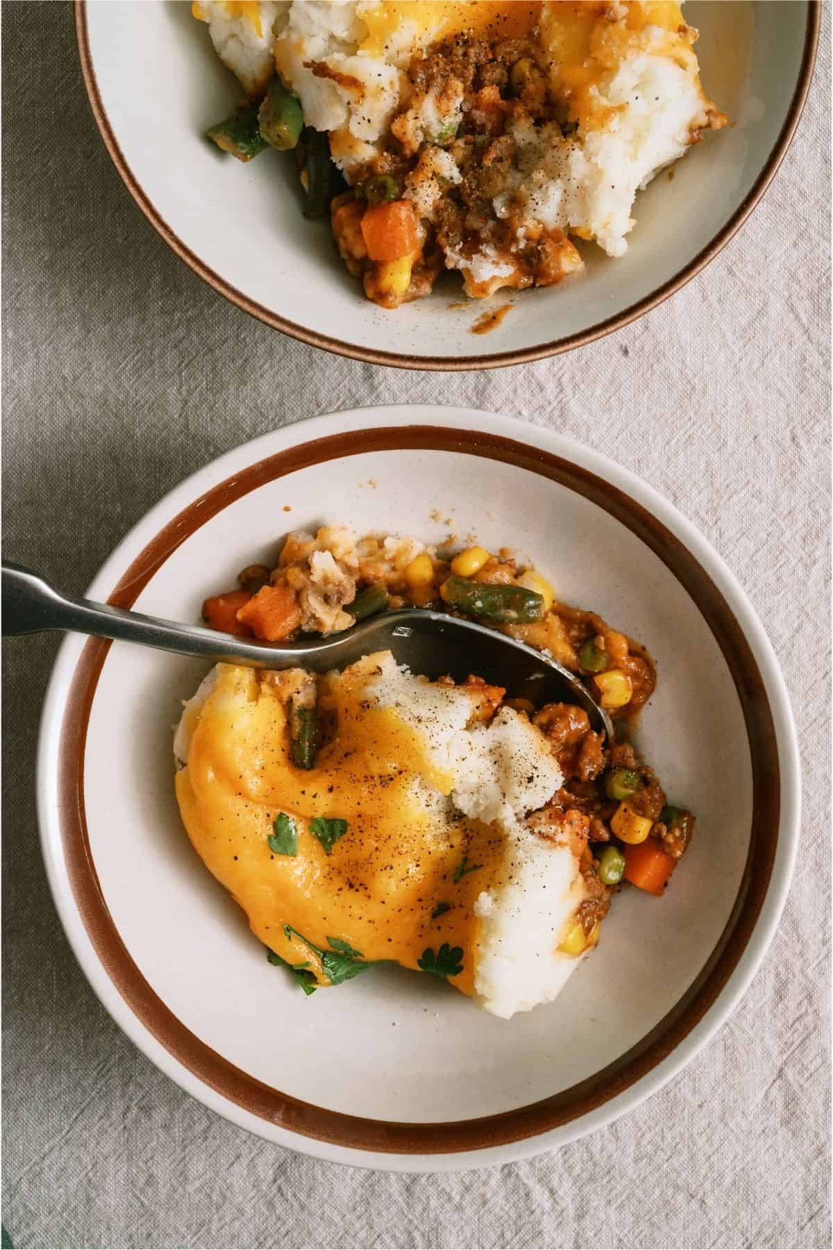 Top view of 2 bowls with servings of Ground Beef Shepherd's Pie in them.