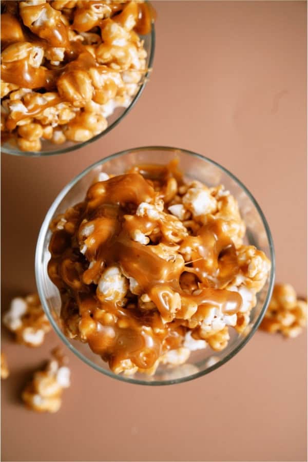 A cup of caramel popcorn with homemade caramel drizzled on top.