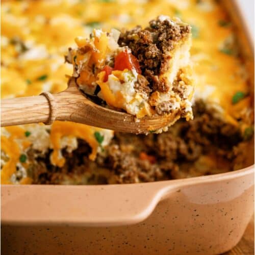 John Wayne Casserole in a casserole dish with a wooden spoon lifting out a scoop.