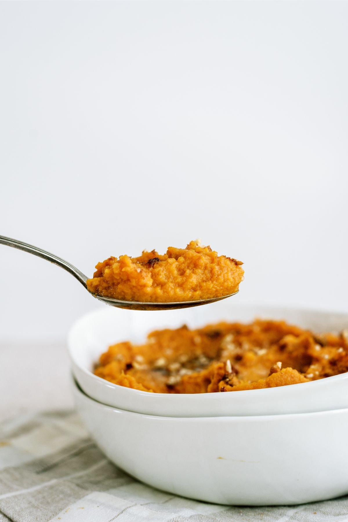 A bowl of Mashed Sweet Potatoes with a spoonful