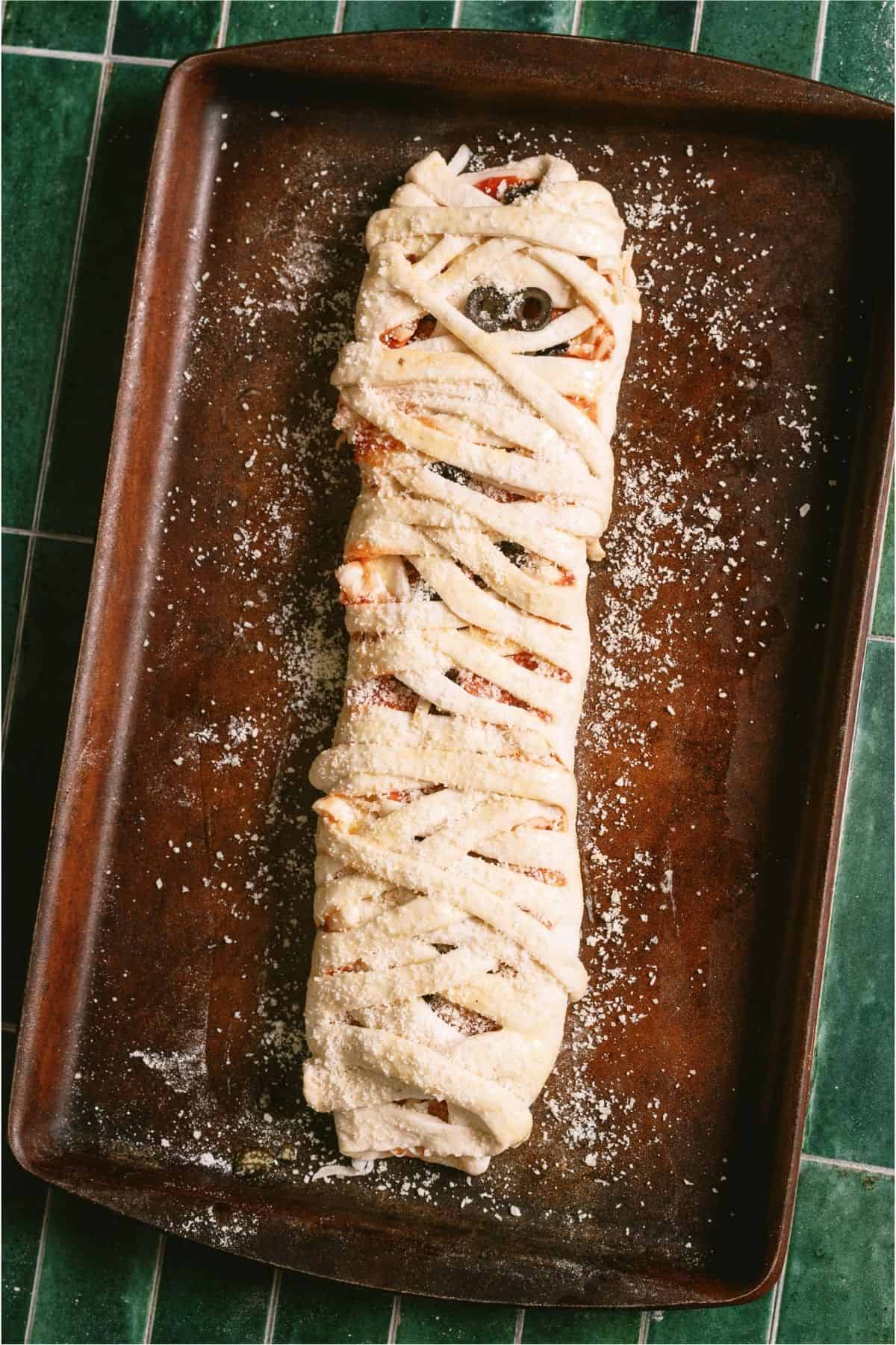 Unbaked Mummy Pizza Braid on a sheet pan.