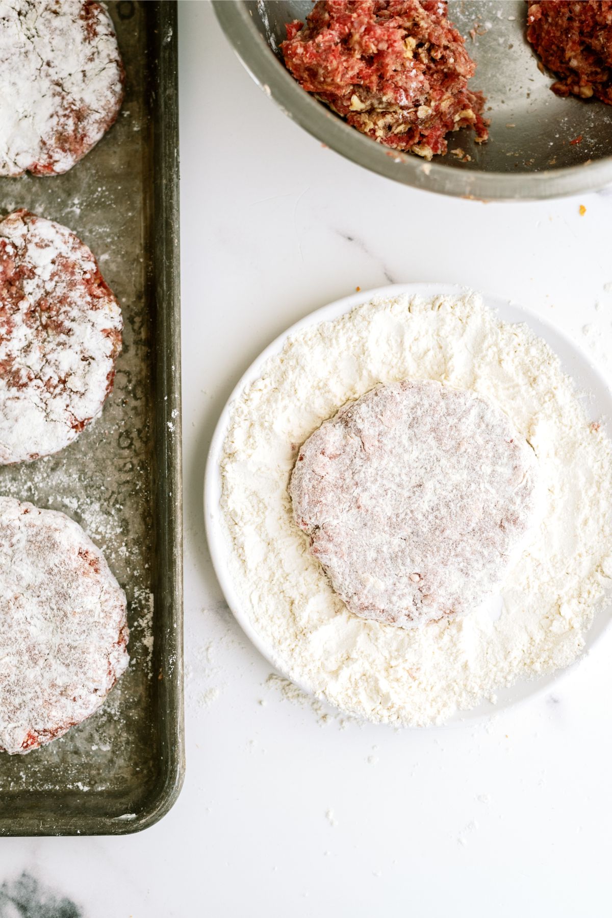 Dredging hamburger patties in flour