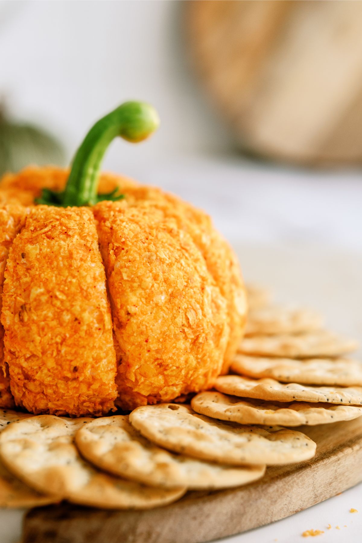 Pumpkin-Shaped Cheeseball with crackers on a cutting board