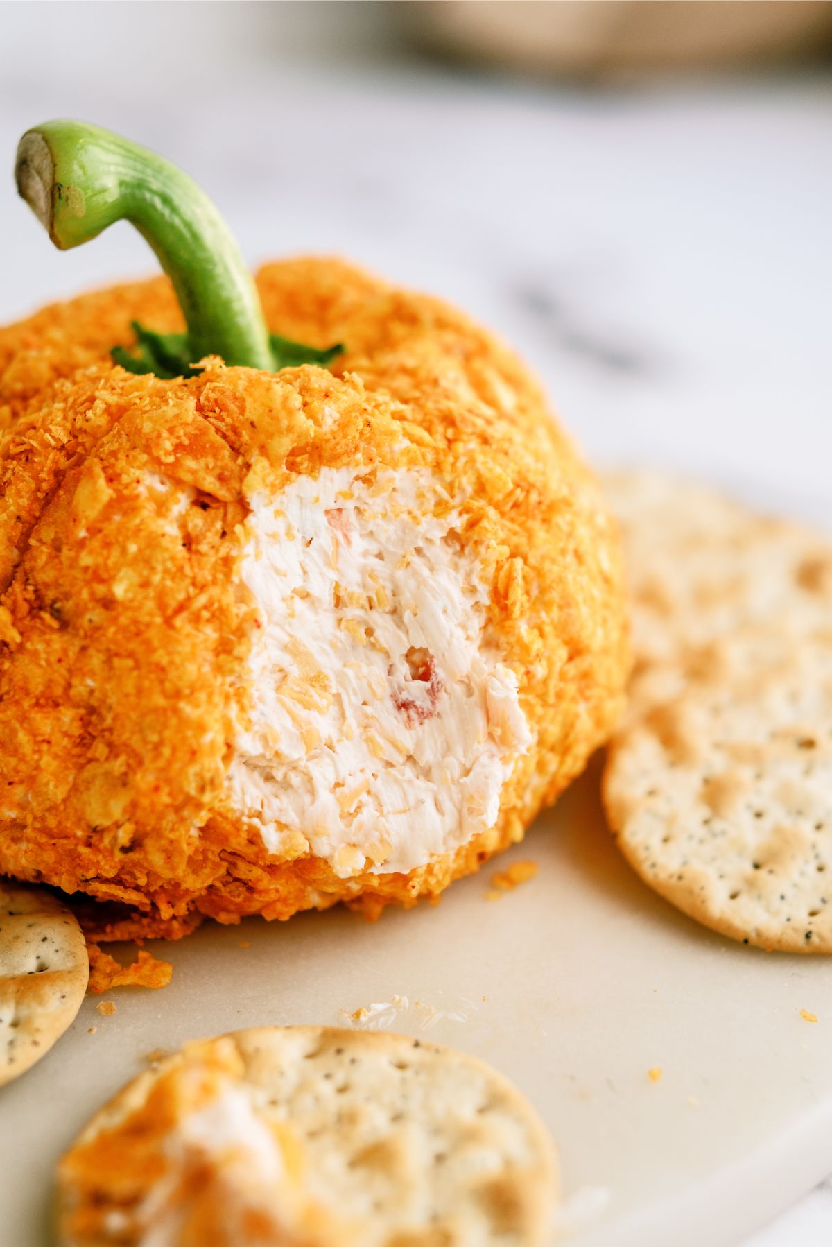Pumpkin-Shaped Cheeseball with a scoop missing surrounded by crackers