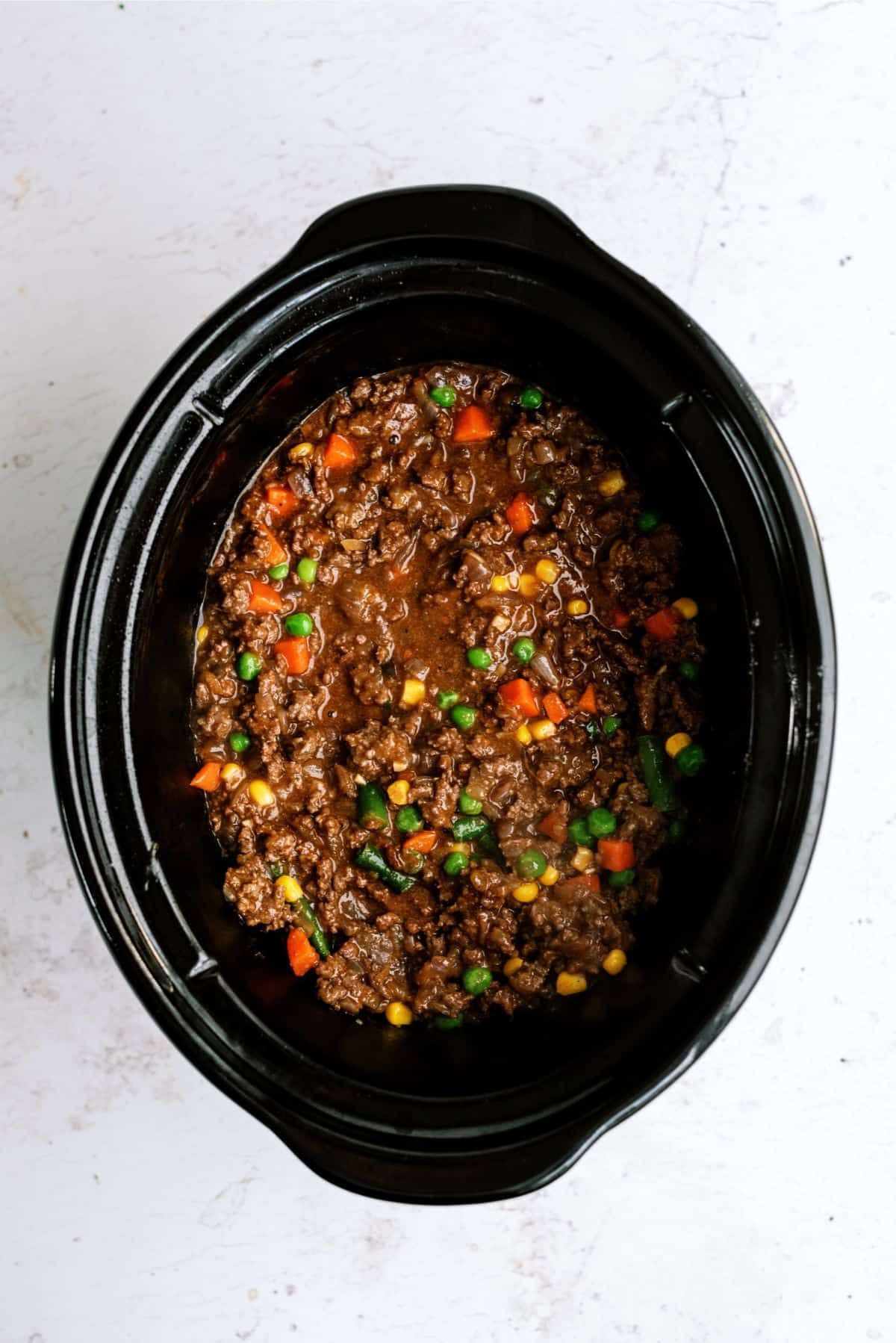 Meat and vegetable mixture in the bottom of a slow cooker