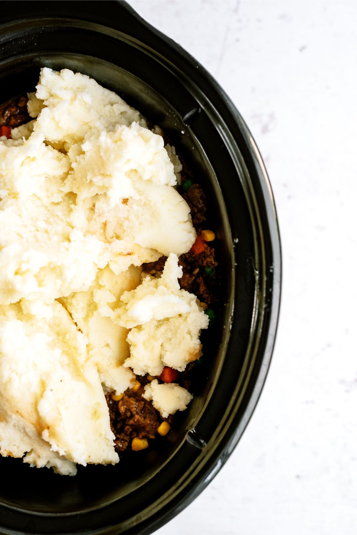 Prepared mashed potatoes on top of meat mixture in the slow cooker