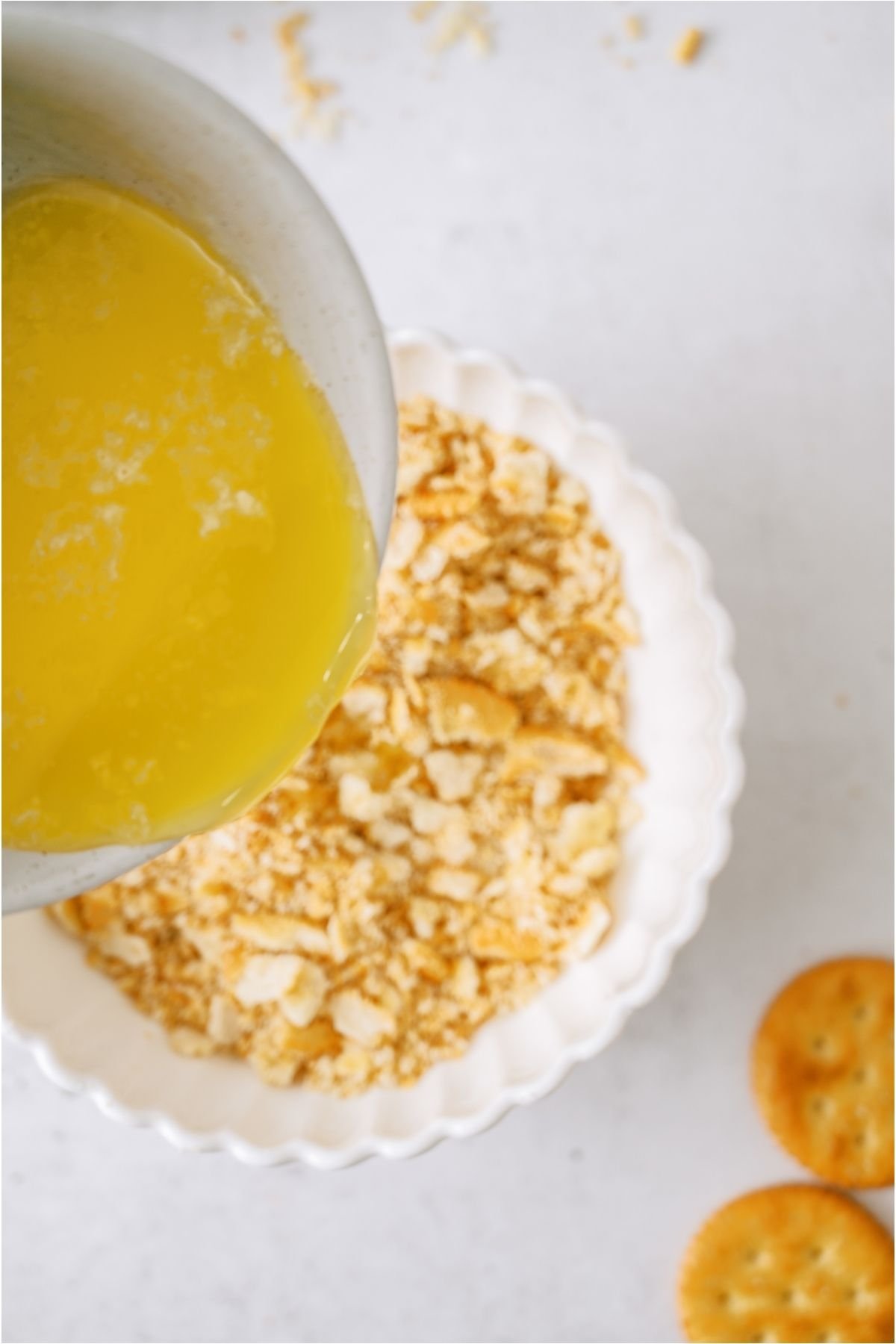 Pouring melted butter into a bowl of crushed ritz crackers.