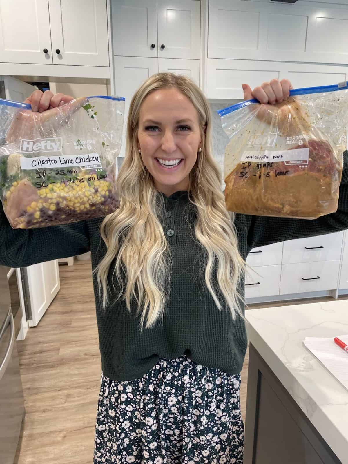 kendra holding her prepped freezer meals in the air