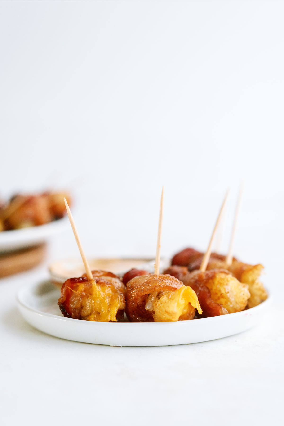 Bacon Wrapped Tater Tots with Cheese on a plate with sauce