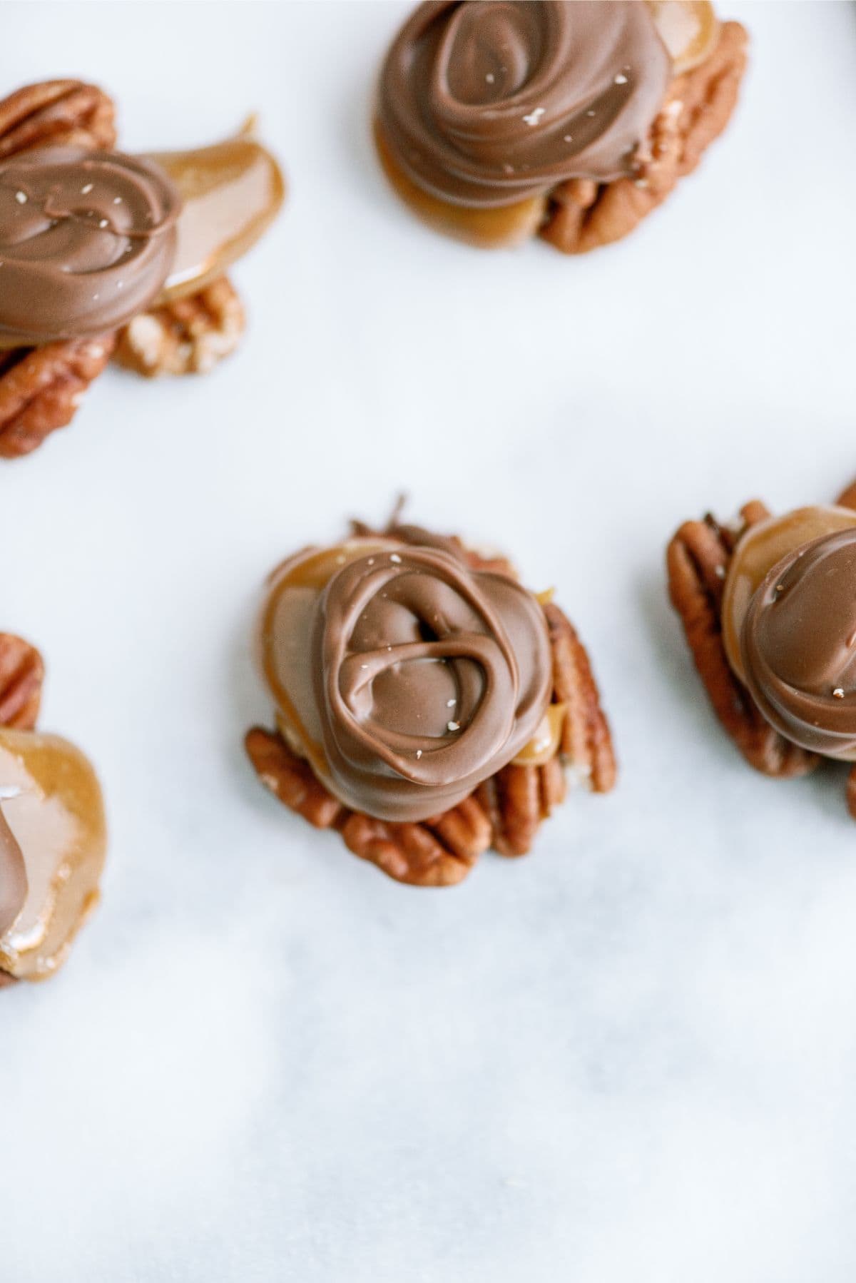 Top view of Chocolate Caramel Pecan Turtles on parchment paper