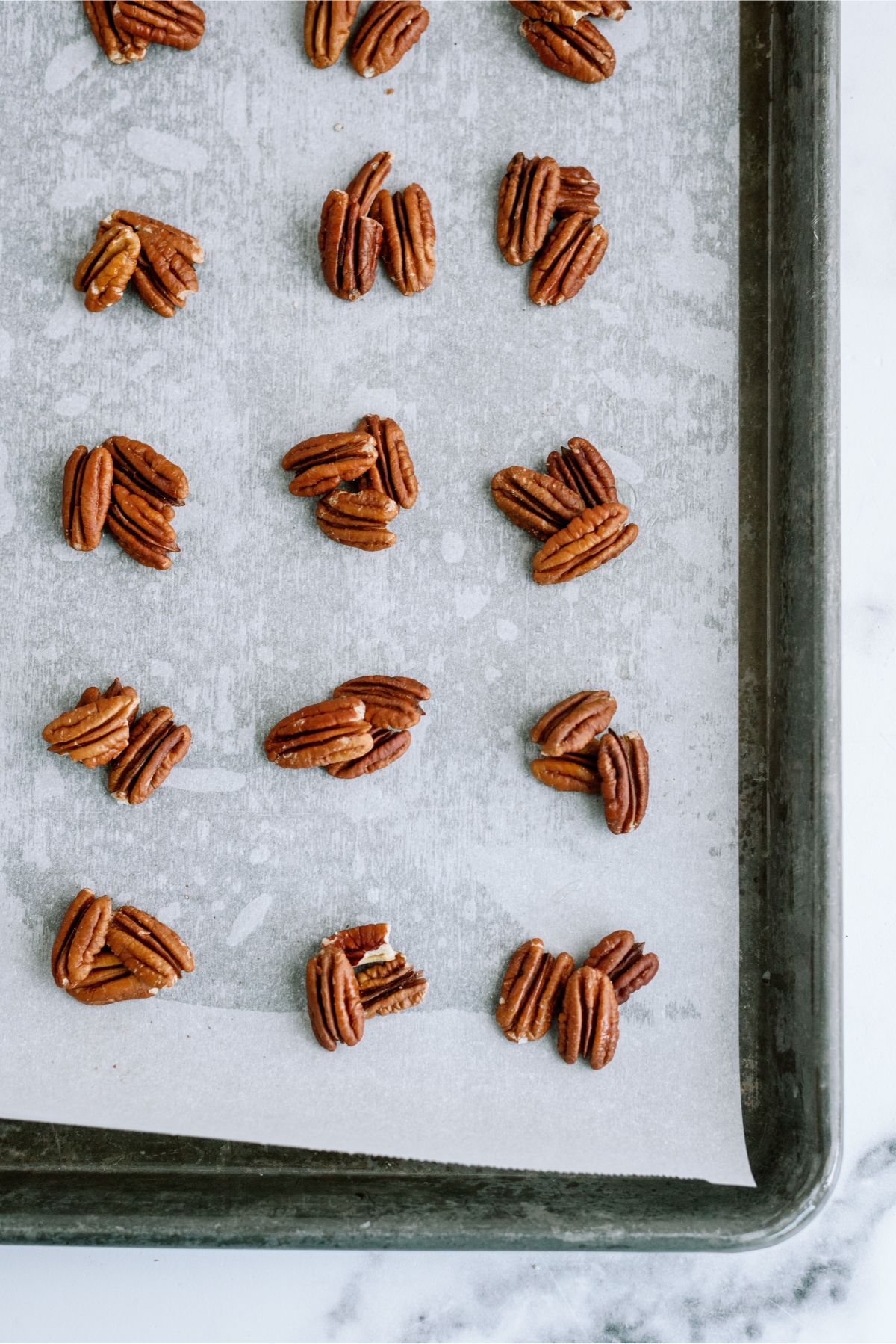 Pecans grouped in 3s on baking sheet