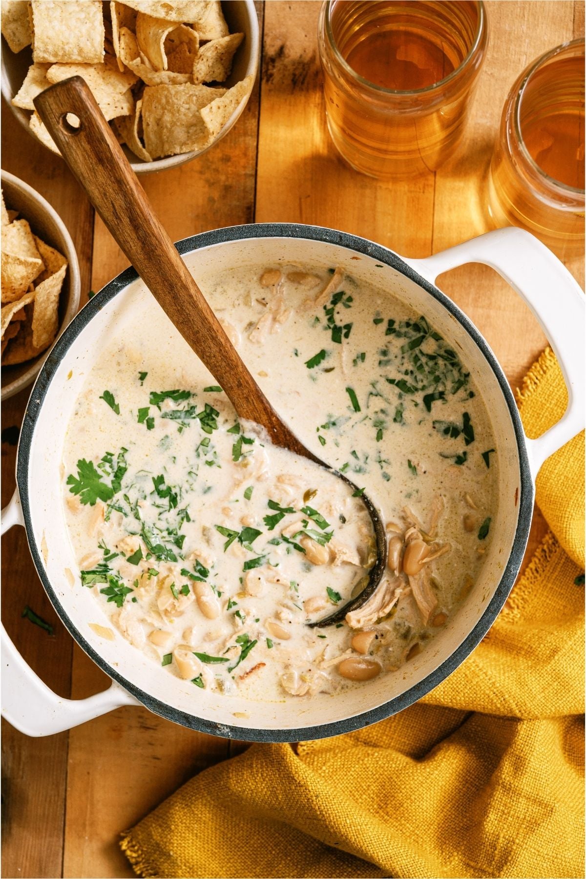 Top view of a pot of Creamy White Chicken Chili with a wooden spoon.