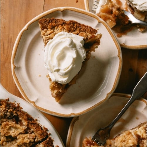 Top view of a slice of Dutch Apple Pie on a plate topped with whip cream.