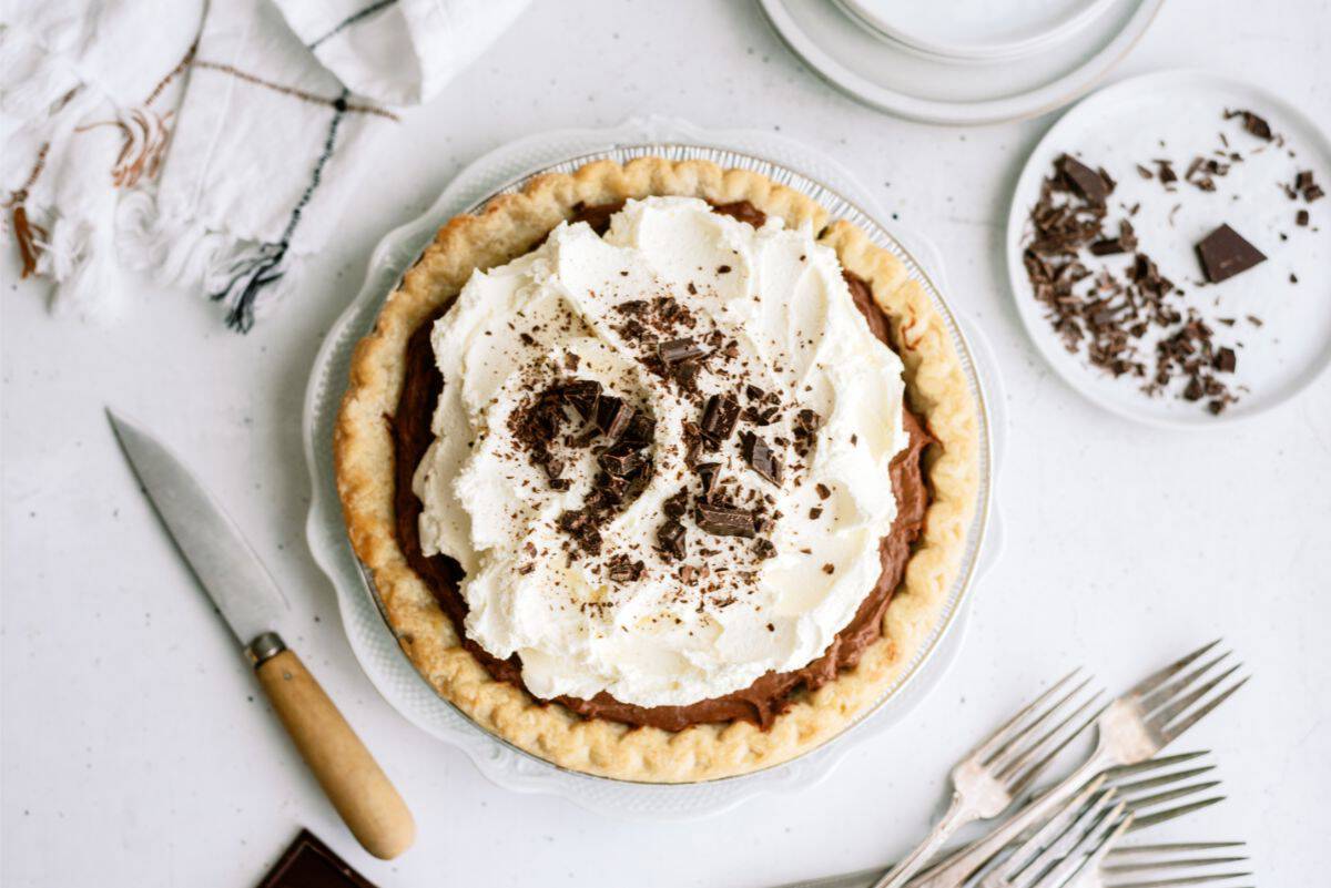 Top view of a Chocolate Cream Pie on a countertop with utensils.