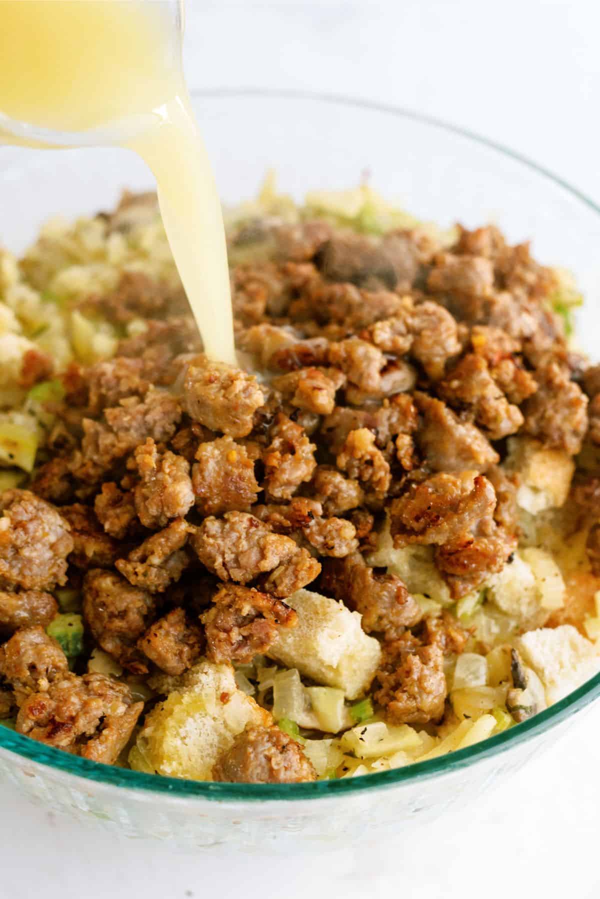 Pouring chicken stock on top of ingredients for Easy Homemade Sausage Stuffing