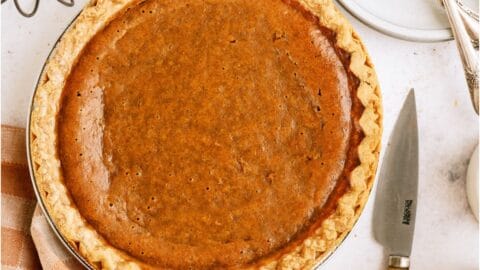Top view of an Easy Pumpkin Pie on a table with decor and a checkered towel.