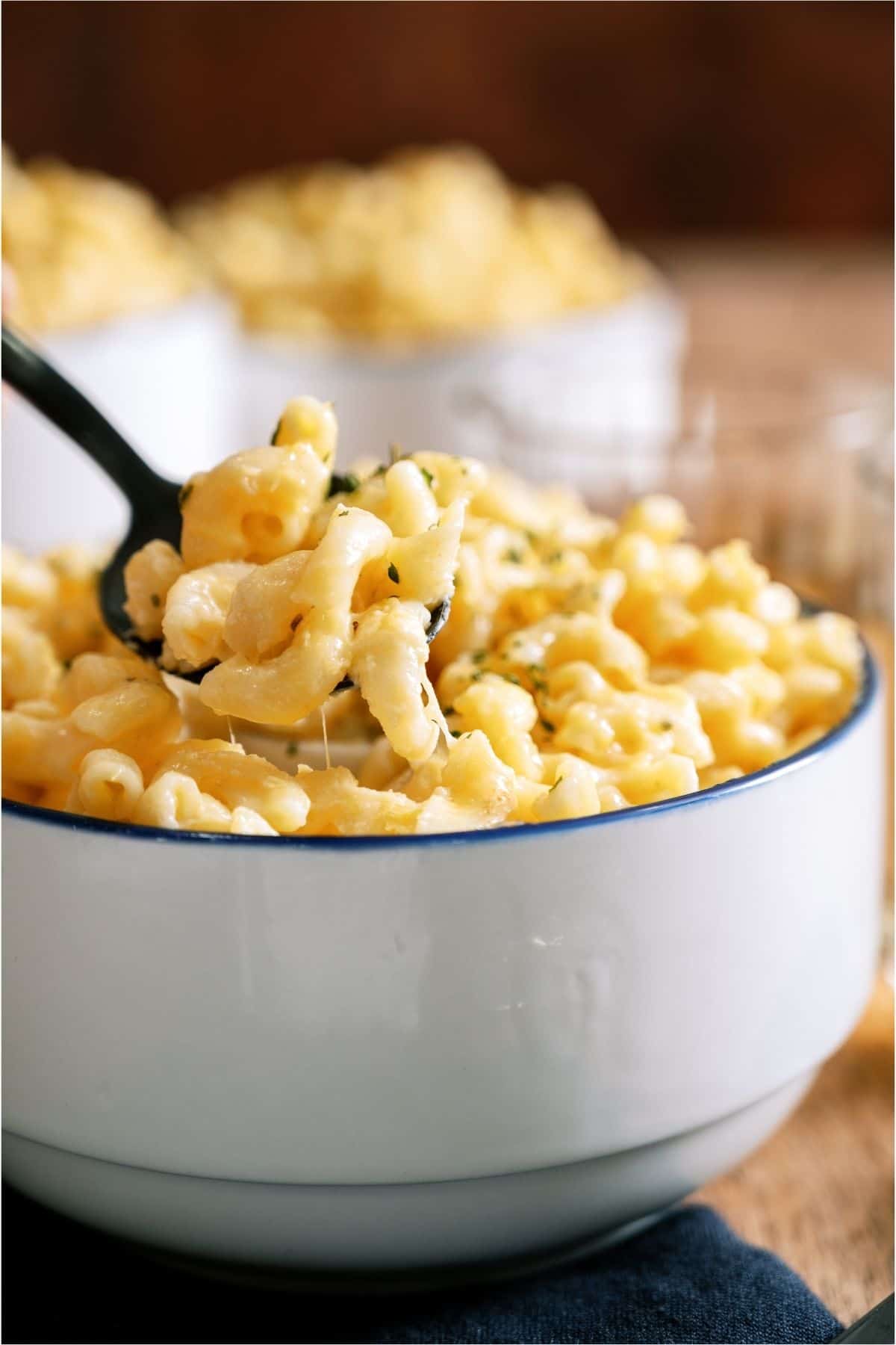 A spoon lifting a bite of Instant Pot Creamy Macaroni and Cheese out of a bowl.