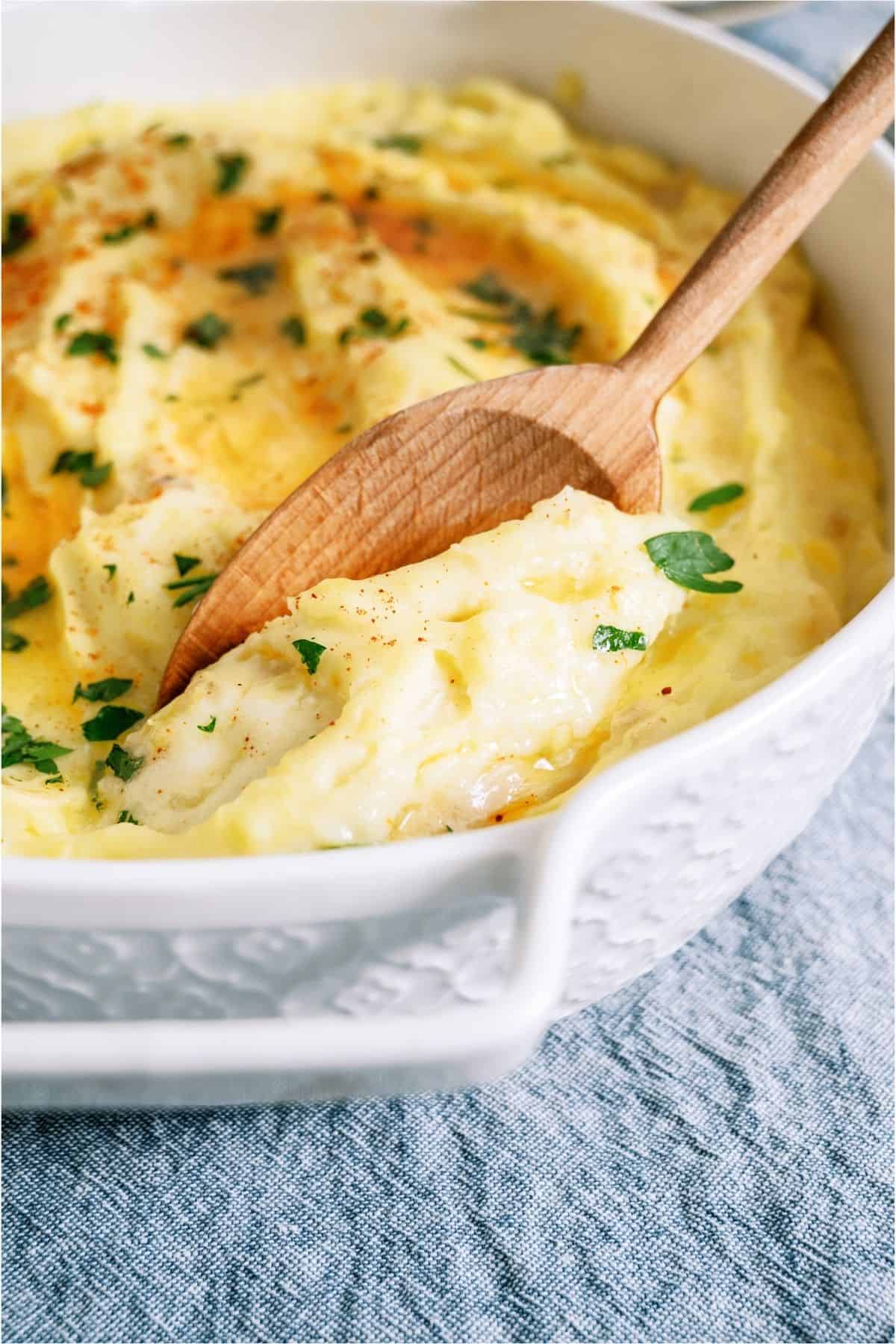 A wooden spoon lifting a scoop of Make-Ahead Mashed Potatoes.