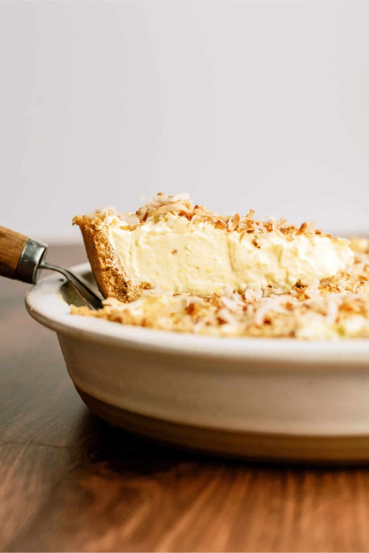 A spatula lifting a slice of No Bake Coconut Cream Pie out of the pie plate.