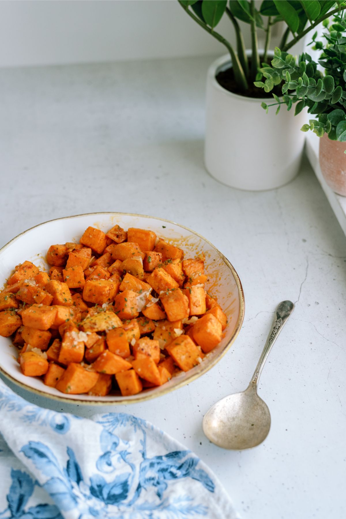 Roasted Parmesan Sweet Potatoes in a serving bowl with a serving spoon