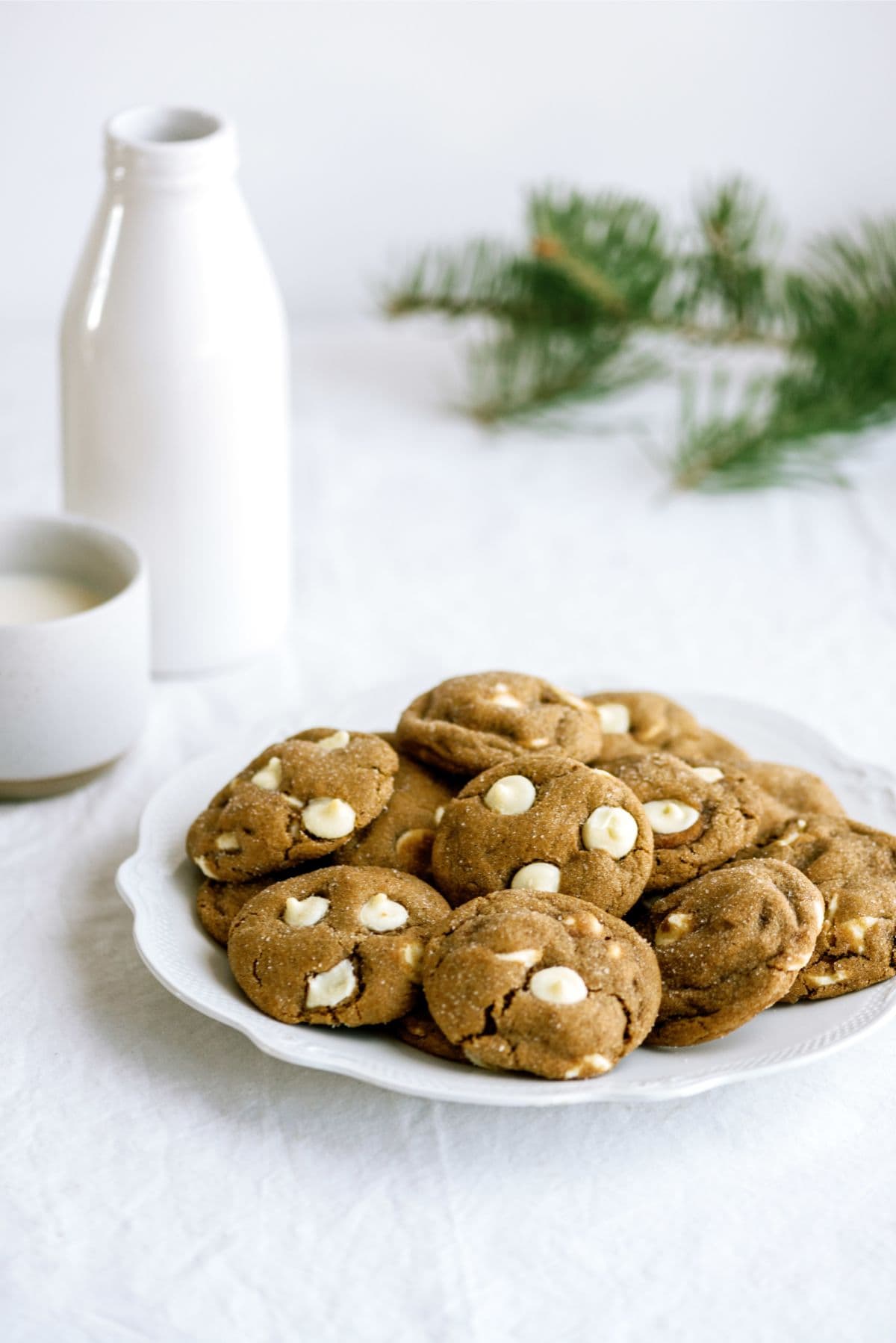 A plate of White Chocolate Chip Gingerbread Cookies with a glass pitcher in the background.